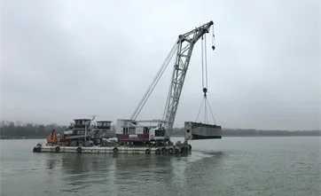 Schwimmkran transportiert Dammbalken am Kranhaken auf der Donau