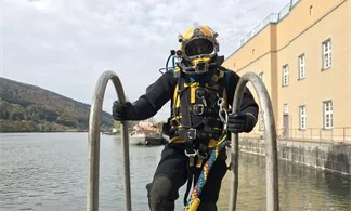 Taucher mit Helm steigt auf einer Leiter aus dem Wasser